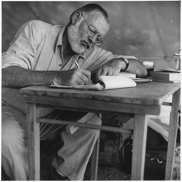 720px-Ernest_Hemingway_Writing_at_Campsite_in_Kenya_-_NARA_-_192655.jpg