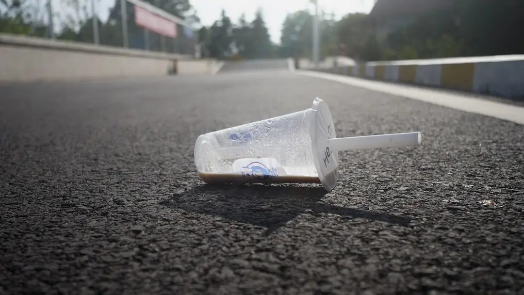 A discarded plastic cup with a straw on the road